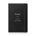 Schwarzes Hardcover-Notizbuch „Danke für deine leisen Wunder“ mit elfenbeinfarbener Typografie und kleinem goldfarbenem Ornament, Vorderansicht.