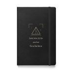 Schwarzes Hardcover-Notizbuch „Zwischen Zelten wachsen Geschichten“ mit heller Typografie und Zeltmotiv