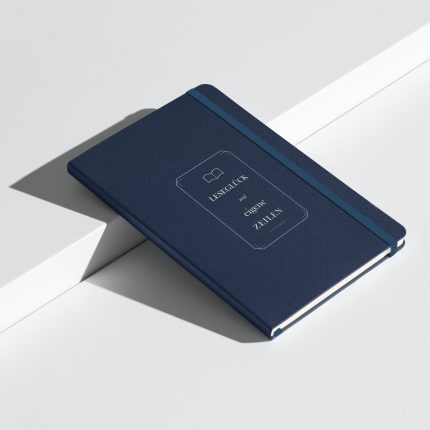 Marineblaues Hardcover-Notizbuch „Leseglück und eigene Zeilen“ im klassischen Buchdesign, schräge Ansicht.