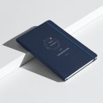 Marineblaues Notizbuch mit cremefarbener Schrift und goldfarbenen Umlaufbahnen, schräge Ansicht