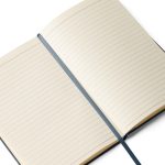 Geöffnetes Notizbuch „Leseglück und eigene Zeilen“ mit cremefarbenen linierten Seiten und Lesebändchen.