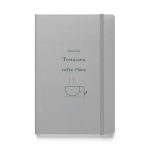 Silbernes Hardcover-Notizbuch „Zwischen Teetassen reifen Pläne“ mit dunkelgrüner Schrift und Tassenmotiv