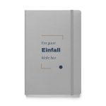 Silbernes Hardcover-Notizbuch „Ein guter Einfall bleibt hier“ mit dunkelblauer Typografie und kupferbraunen Winkeln – Vorderansicht