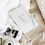 Weißes Hardcover-Notizbuch „Mein Atem findet freie Zeilen“ mit dunkelgrüner Typografie, schräge Ansicht auf hellem Stoff